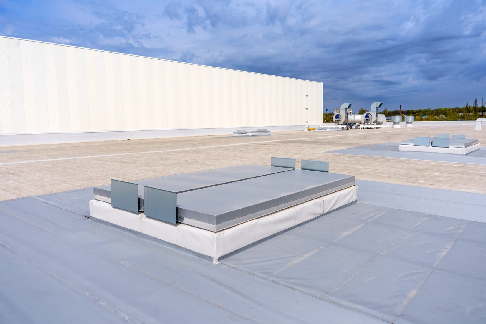 White metal sheet rooftop on a commercial building under blue sky