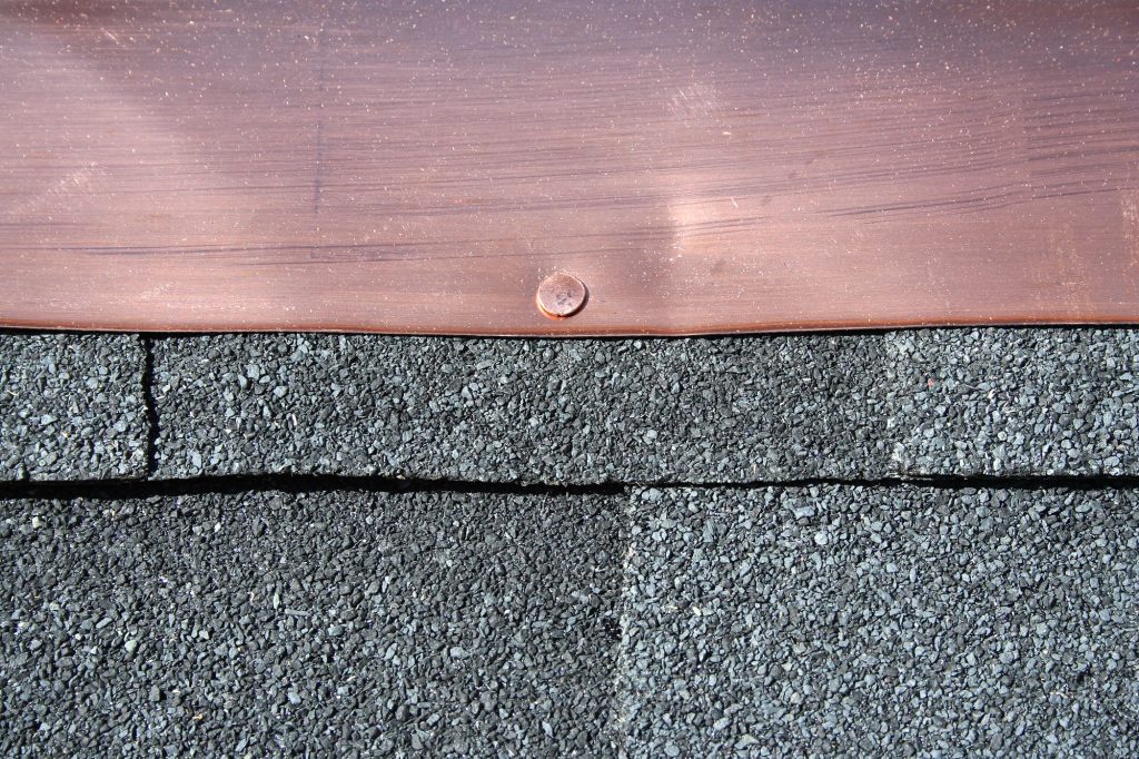 Close-up of premium asphalt shingles with copper flashing installed by Genesis Roofing