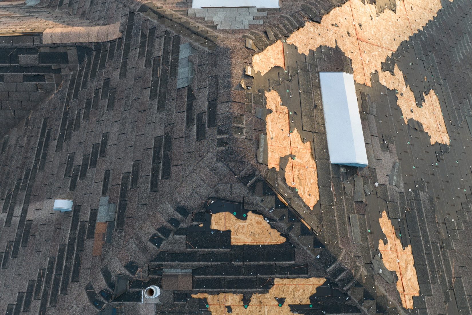 Wind-damaged shingles on a residential roof before Genesis Roofing repair